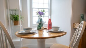 A dining table with two chairs, a vase with flowers, and a bottle of dish soap.