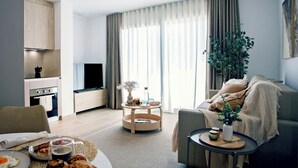 A modern living room with a sofa, a coffee table, a dining table with breakfast items, a kitchen area, and a large window with curtains. - REM II Torrevieja (Torrevieja)