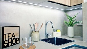 A modern kitchen with a sink, a wooden sign, a plant, and a jar with utensils. - REM II Torrevieja (Torrevieja)