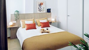 A neatly arranged hotel room with a bed, bedside tables, a wall-mounted shelf, a door, and a plant. - REM II Torrevieja (Torrevieja)