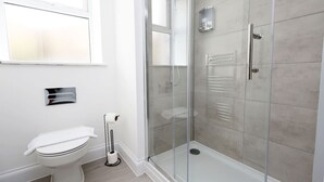 Une salle de bain moderne équipée de toilettes, d’une douche à parois de verre et d’un porte-serviettes.
