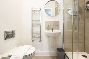 A modern bathroom with a toilet, a sink, a glass shower enclosure, a towel rack, and a mirror. - Work • En-Suite • Fridge & Microwave • Smart TV (Carmarthenshire)