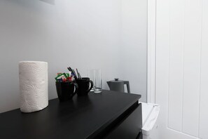 A black table with a white paper towel roll, a black mug with pens and a glass, and a small gray container. - Work • En-Suite • Fridge & Microwave • Smart TV (Carmarthenshire)