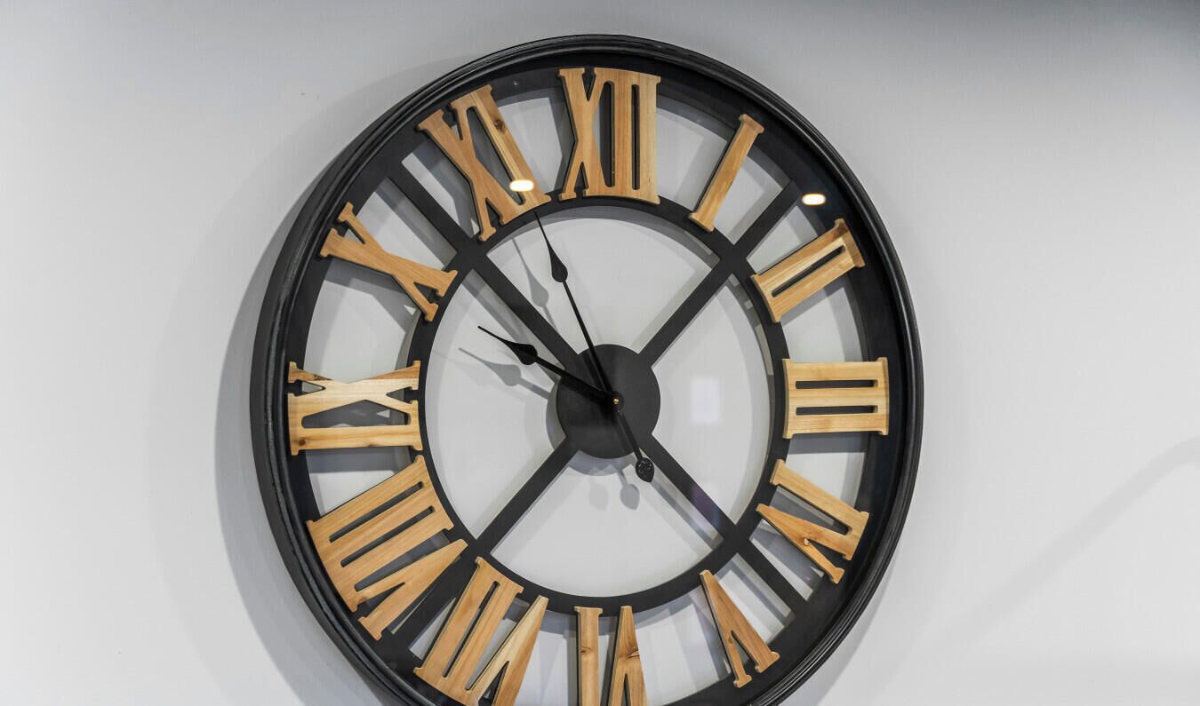 Une horloge murale ronde, dotée de chiffres romains et d’un design minimaliste.