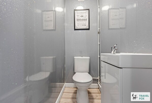 A bathroom with a toilet, sink, and a framed sign on the wall.
