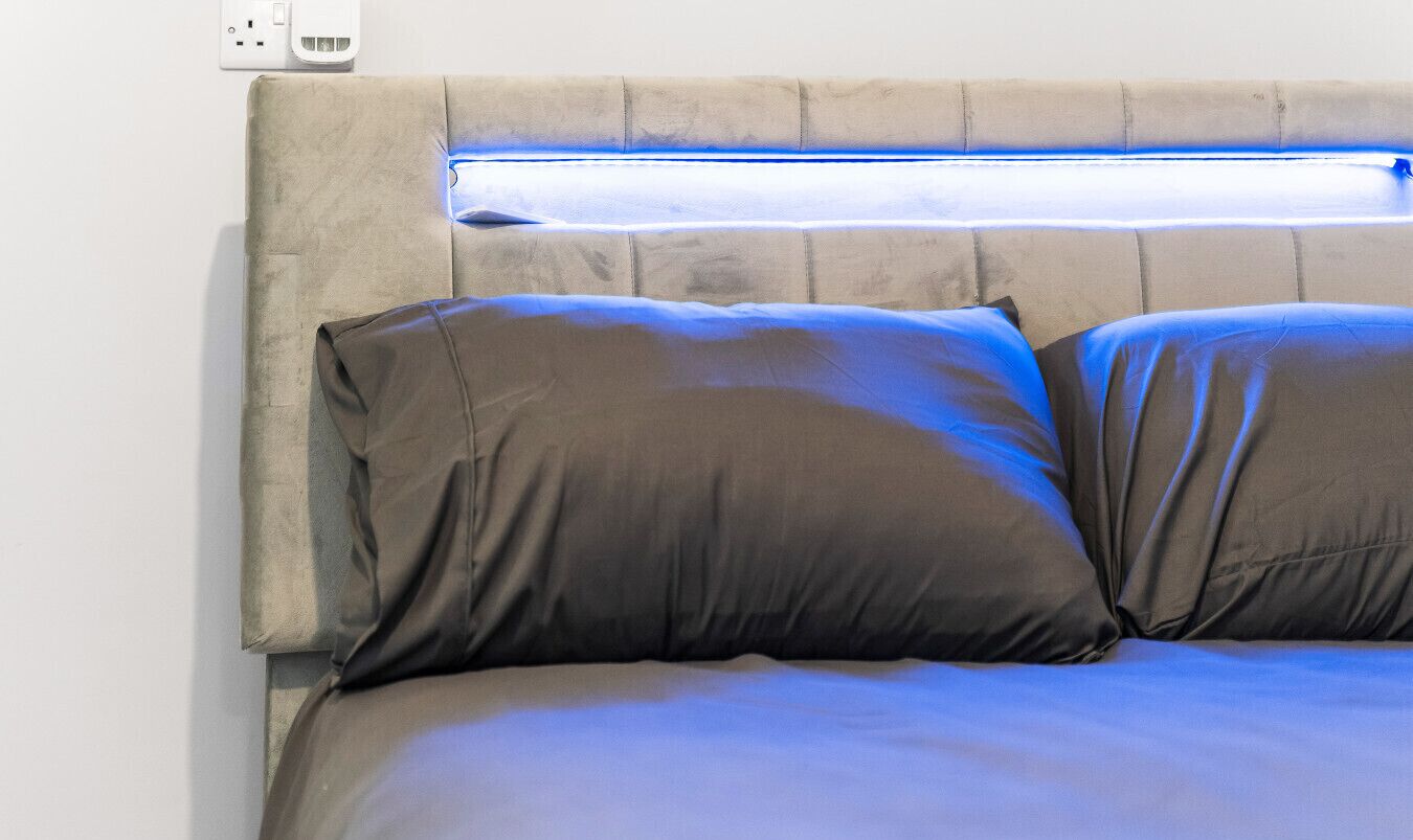 A bed with a headboard, pillows, and a light fixture.