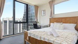 Una camera d'albergo con un letto grande, una scrivania e vista su alti edifici.