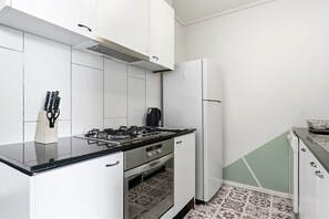 A compact kitchen with white cabinets, a gas stove, a built-in oven, and a refrigerator. - Stunning CBD Penthouse Top-Floor Living with Pool, Gym & Skyline Views (Melbourne)