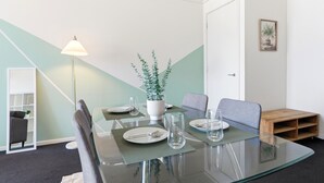 Un'elegante zona pranzo con tavolo in vetro, sedie, una pianta in vaso e una lampada.