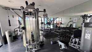Una palestra con diverse macchine per esercizi, manubri e attrezzature cardio.