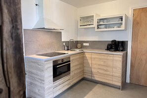 A modern kitchen with a built-in oven, a sink, and a coffee maker.