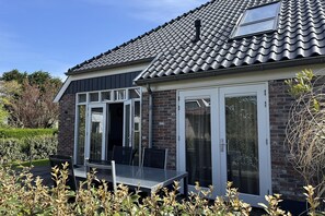 Ein Haus mit Ziegeldach, Backsteinfassade und einer Schiebetür aus Glas.