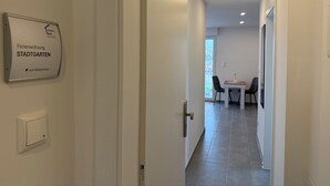 Un corridoio che conduce a una sala da pranzo con tavolo e sedie, un cartello al muro e un interruttore della luce.