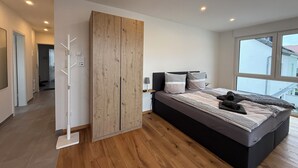 Una camera da letto moderna con un letto grande, un'armadiatura in legno e vista all'esterno da una grande finestra.