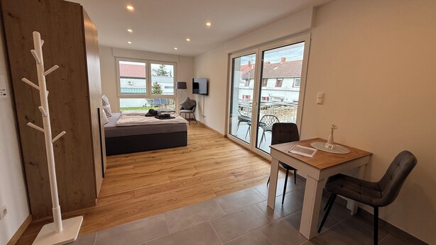 Un appartamento moderno con un letto grande, un'area pranzo e vista attraverso una porta scorrevole in vetro.
