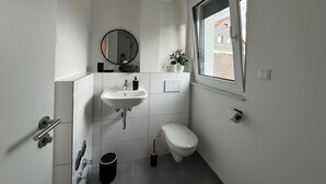 Un bagno moderno con lavandino, water e finestra.