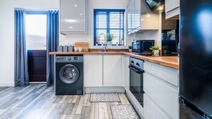Eine kleine Küche mit Waschmaschine, Backofen und einem großen Kühlschrank.