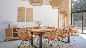 Un comedor con una mesa de madera, sillas de mimbre e iluminación colgante tejida.