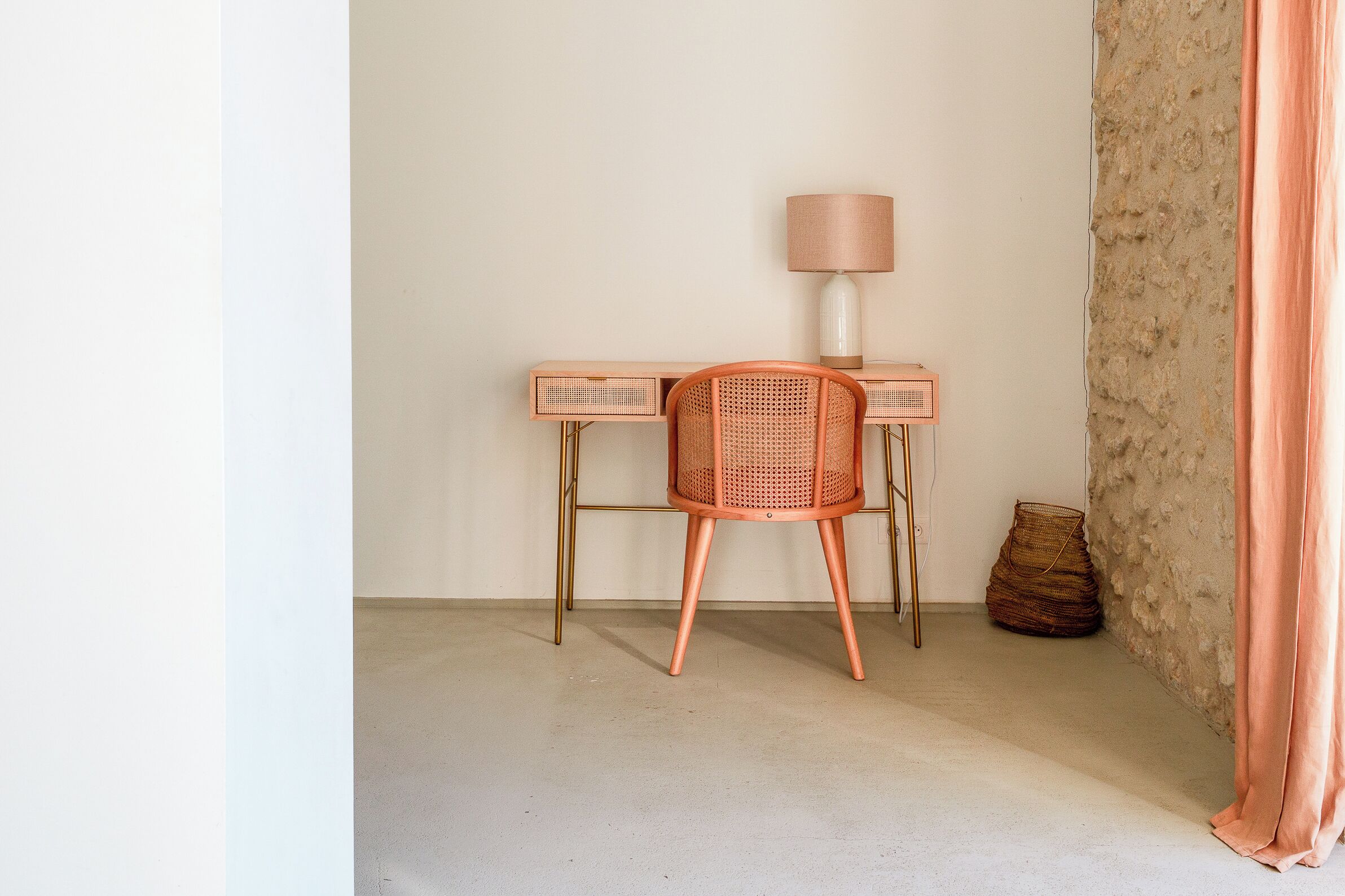 A workspace with a chair, desk, lamp, and a woven basket.