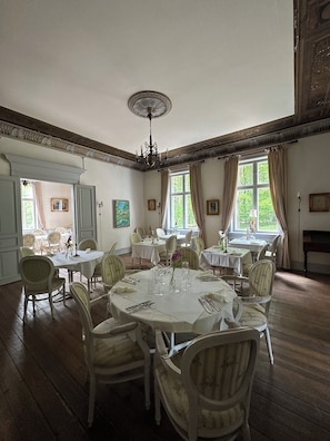 Un comedor con mesas redondas, sillas y un candelabro.