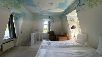 A room with a bed, two chairs, a table, and a window.