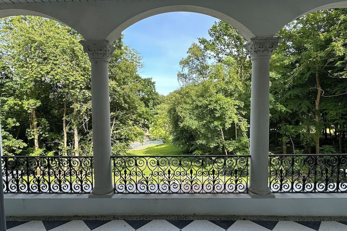 A covered outdoor area with columns and a view of a green landscape.