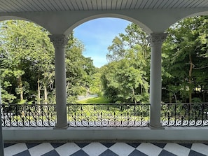 A covered outdoor area with columns and a view of a green landscape.