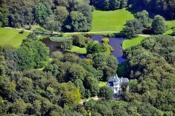 An aerial view of a large estate with a prominent house, a pond, and extensive greenery. - Liselund Ny Slot (Borre)