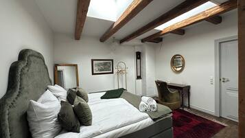 A bedroom with a bed, a mirror, a dresser, and a skylight.