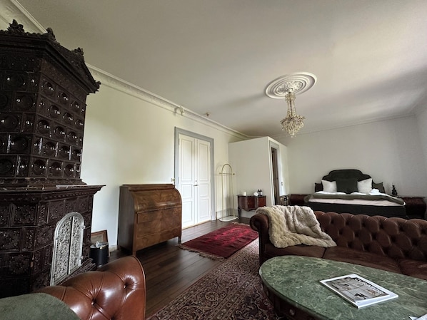 A traditional room with a wooden cabinet, a green marble table, a brown leather sofa, and a bed with a dark headboard. - Liselund Ny Slot (Borre)