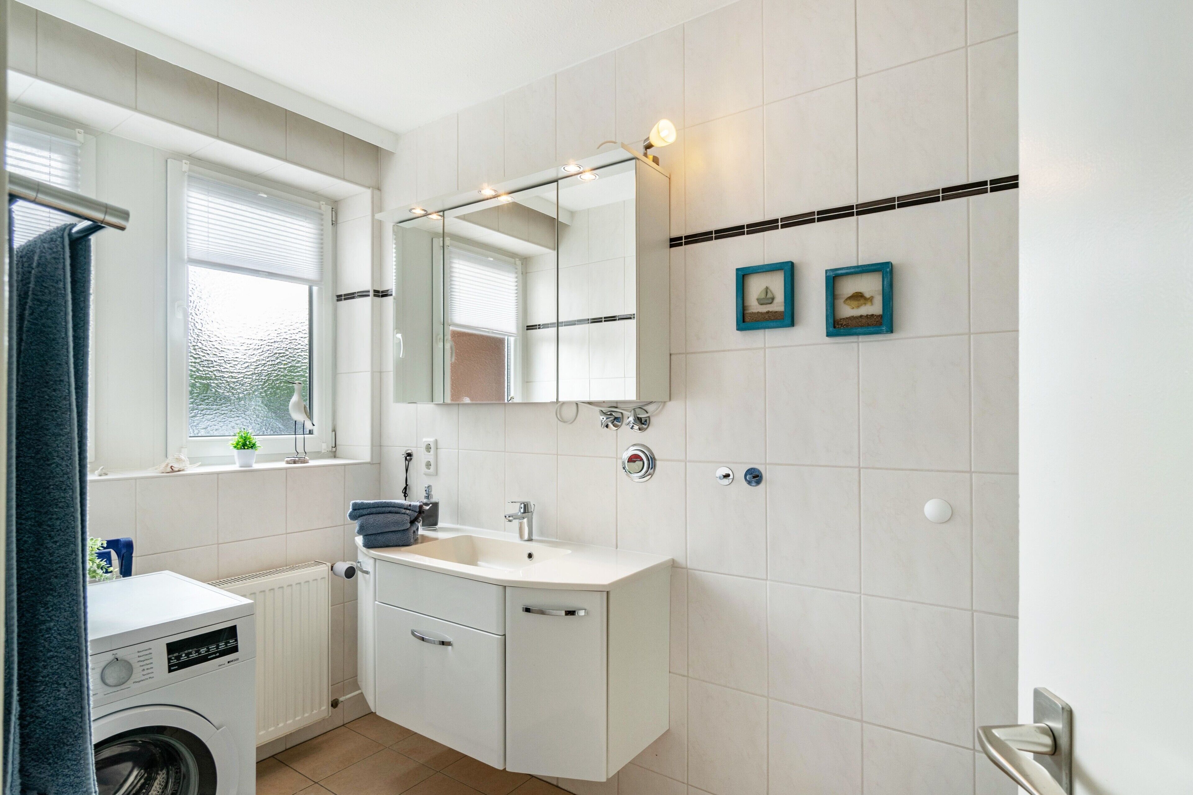 A modern bathroom with a washing machine, a sink, and a mirror.