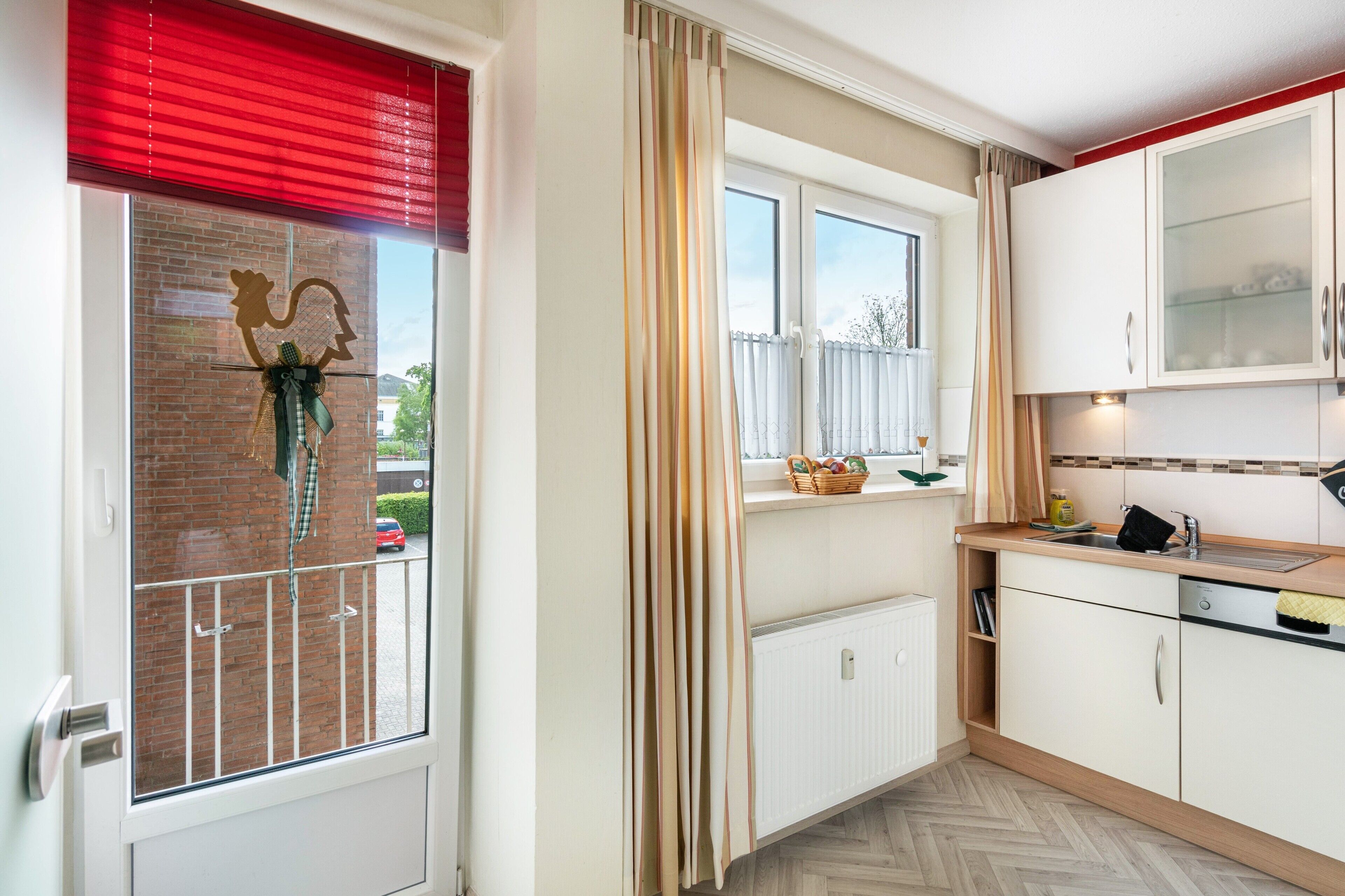 A kitchen with a window, a radiator, and a door.