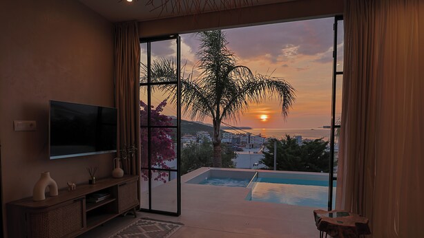 A room with a TV, a pool, and a view of the sunset. - Ksamil Villa with Private Pool & Jacuzzi – Serein (Ksamil)