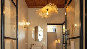 A narrow hallway with a wooden ceiling, a glass door on the right, a white sink with a mirror above it, and a cactus plant in a woven basket. - Ksamil Villa with Private Pool & Jacuzzi – Serein (Ksamil)