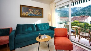 Un salon avec un canapé de couleur turquoise, une petite table ronde en verre et un tableau accroché au-dessus.
