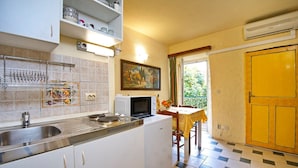 A compact kitchen with a sink, stove, microwave, and a dining area with a table and chairs. - One-Bedroom Apartment Senko A2 (Trpanj)