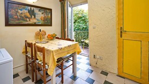 A dining area with a table set for two, a painting on the wall, and a yellow door. - One-Bedroom Apartment Senko A2 (Trpanj)