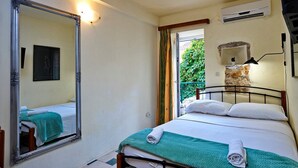 Un dormitorio con cama, espejo, equipo de aire acondicionado y vistas a zonas verdes.