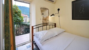 Un dormitorio con cama, ventana, equipo de aire acondicionado, lámpara de pared y un cuadro enmarcado.
