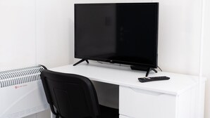 A white desk with a black TV, a remote control, and a black chair. - Private En-Suite Studio with TV, Fridge & Free Parking (Saint Thomas)