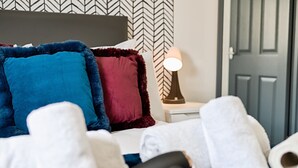 A bed with multiple pillows, a bedside lamp, and rolled towels. - Private En-Suite Studio with TV, Fridge & Free Parking (Saint Thomas)