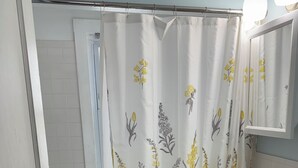 Um banheiro com cortina de chuveiro, pia, espelho e vaso sanitário.