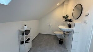 Un baño moderno con tragaluz, inodoro, lavabo y espejo.