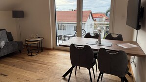 Una habitación con una mesa de comedor, sillas, un sofá, una lámpara de pie y un televisor.