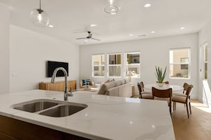 A modern kitchen with a large island, double sink, and a dining area with a round table and chairs. - Villa #44 At Bloomington Country Club 4 Bedroom Condo (St. George)