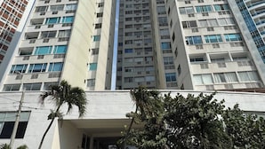 Un edificio alto con varios pisos, una escalera que conduce a la entrada y un cielo despejado.