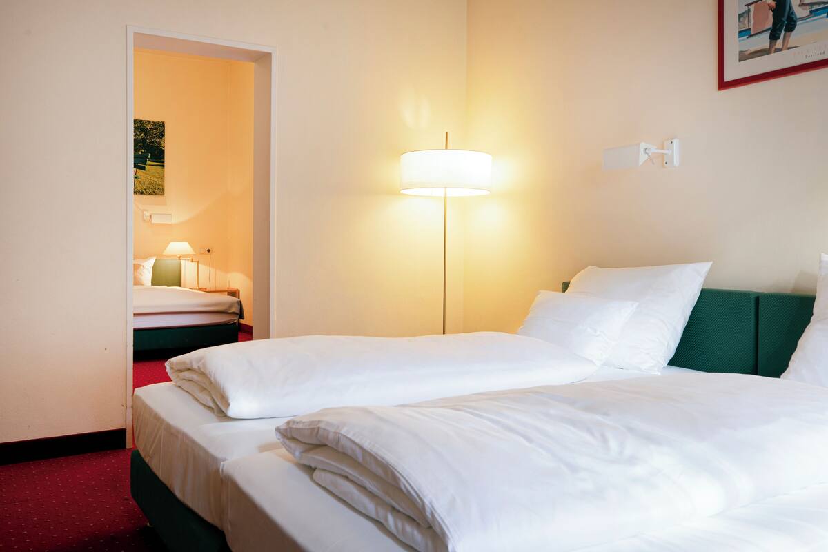 Una habitación de hotel con una cama, una mesita de noche, una lámpara y un cuadro en la pared.