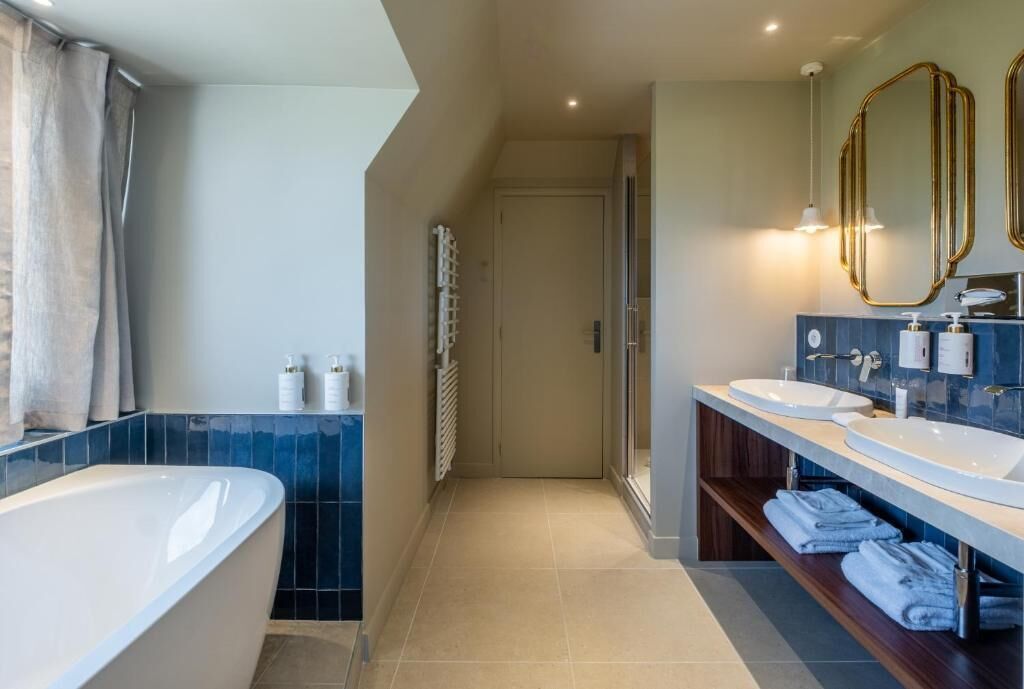 A modern bathroom with a bathtub, two sinks, a shower, and a towel rack.