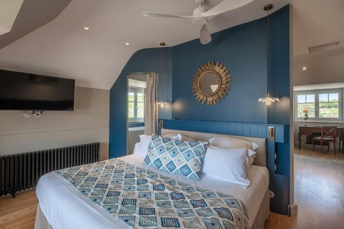A bedroom with a bed, a ceiling fan, a wall-mounted TV, and a window.