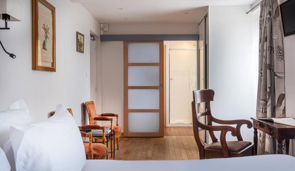 Une chambre d’hôtel comprenant un lit, un bureau, une chaise, une bibliothèque et une porte donnant sur une autre pièce.